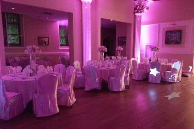 Elegant ballroom with pink linens and floral centerpieces for weddings and events.