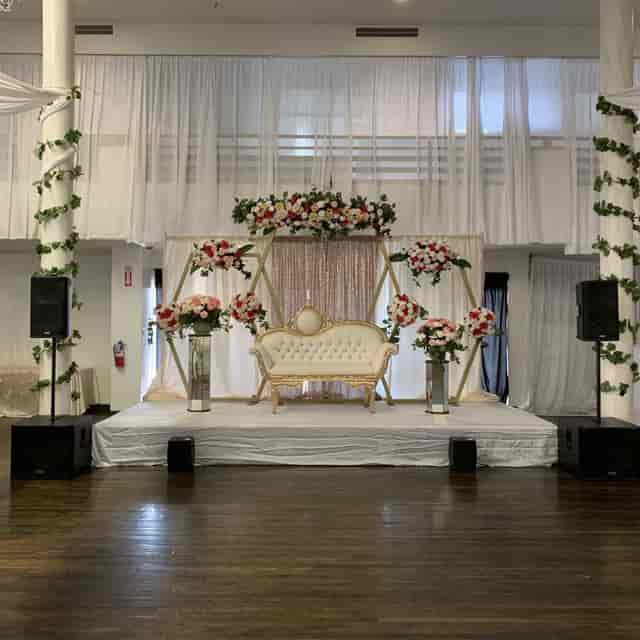 Elegant event stage with white sofa and floral decor, perfect for weddings and celebrations.