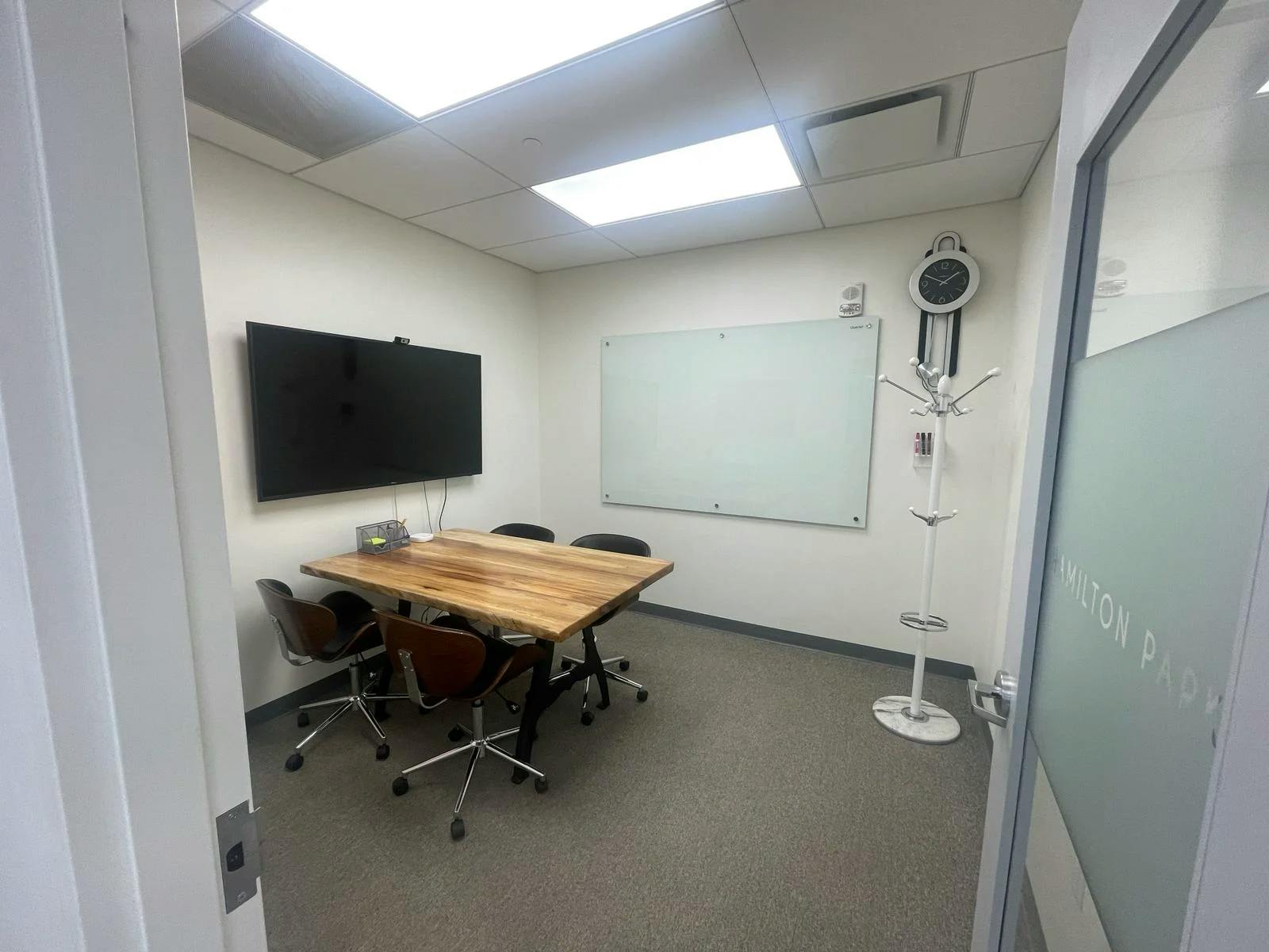 Well-lit meeting room with large screen, ideal for intimate meetings and brainstorming sessions.
