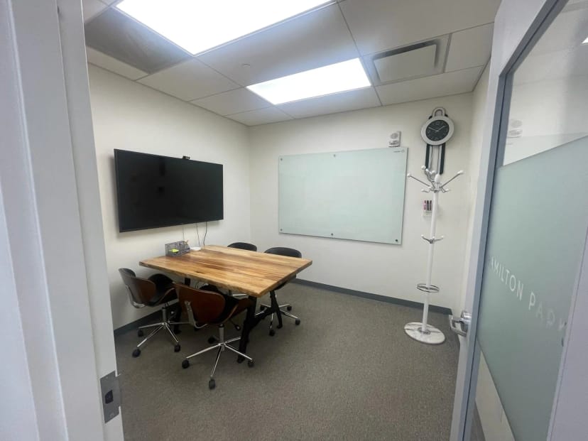 Well-lit meeting room with large screen, ideal for intimate meetings and brainstorming sessions.