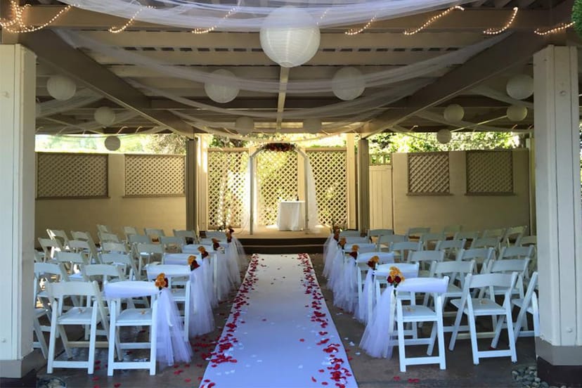 Outdoor wedding venue at Los Gatos Lodge with floral chairs and rose petal aisle.