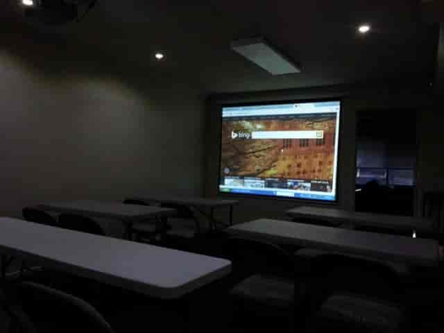 Meeting room with tables, chairs, and projection screen for workshops and training sessions.