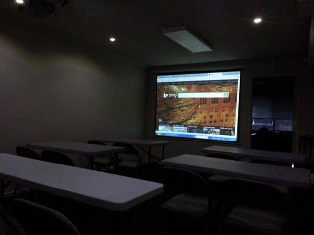Meeting room with tables, chairs, and projection screen for workshops and training sessions.