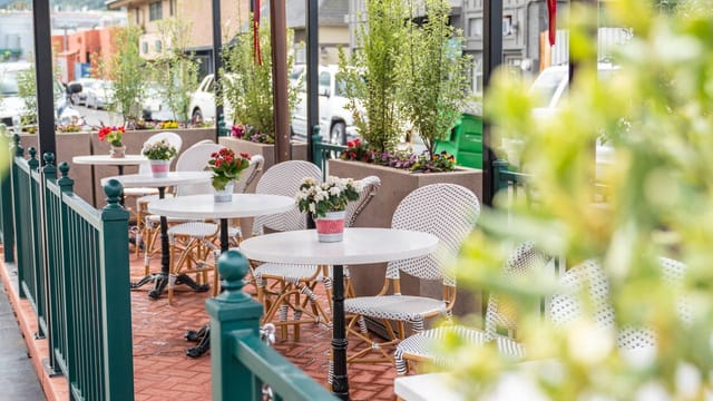 Charming outdoor patio with white tables, ideal for casual meetings and networking events.