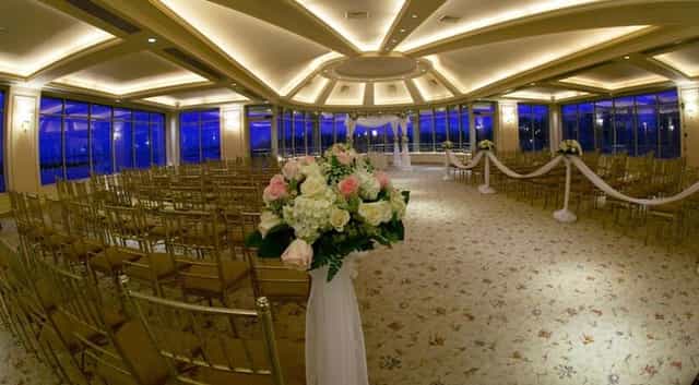 Elegant wedding ceremony at Glen Island Harbour Club with floral arrangements and gold chairs.