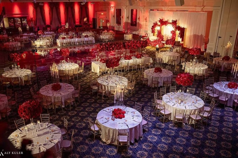 Elegant ballroom at The Legacy Castle with red floral centerpieces for gala events.