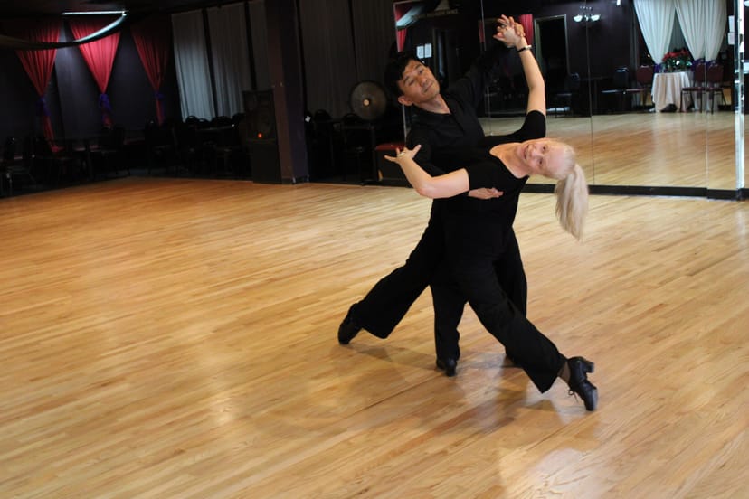 Dynamic dance performance in spacious Imperial Ballroom Dance Studio with polished wooden floor.