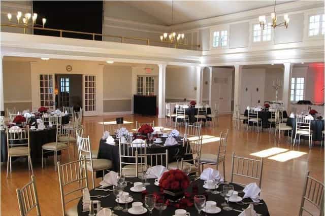 Elegant ballroom with red floral centerpieces, ideal for weddings and corporate events.