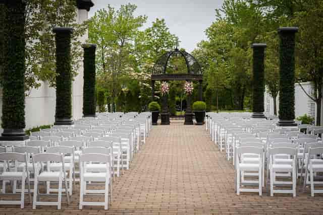Outdoor wedding ceremony at The Gramercy, featuring white chairs and a decorative archway.