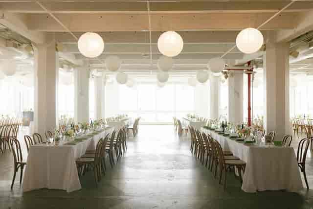 Spacious banquet venue with elegant white tables, ideal for weddings and corporate events.
