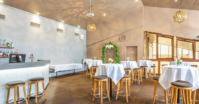 Elegant event space at Jewells Tavern with high-top tables and greenery arch.