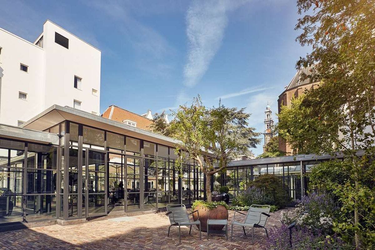 Outdoor event space at Pulitzer Amsterdam with modern glass architecture and lush greenery.
