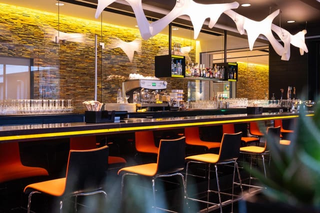 Modern bar at Novotel Amsterdam City with vibrant seating, perfect for events.