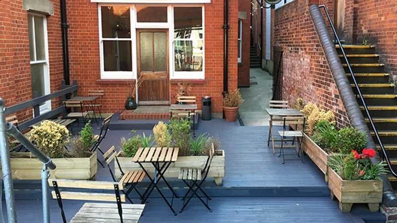 Outdoor networking space at Yard Bar, Stanley Arts London with inviting greenery and seating.