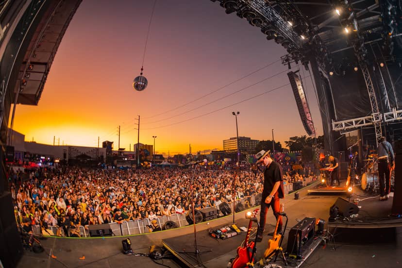 Outdoor concert at RC Cola Plant, vibrant sunset sky, event planning and atmosphere.
