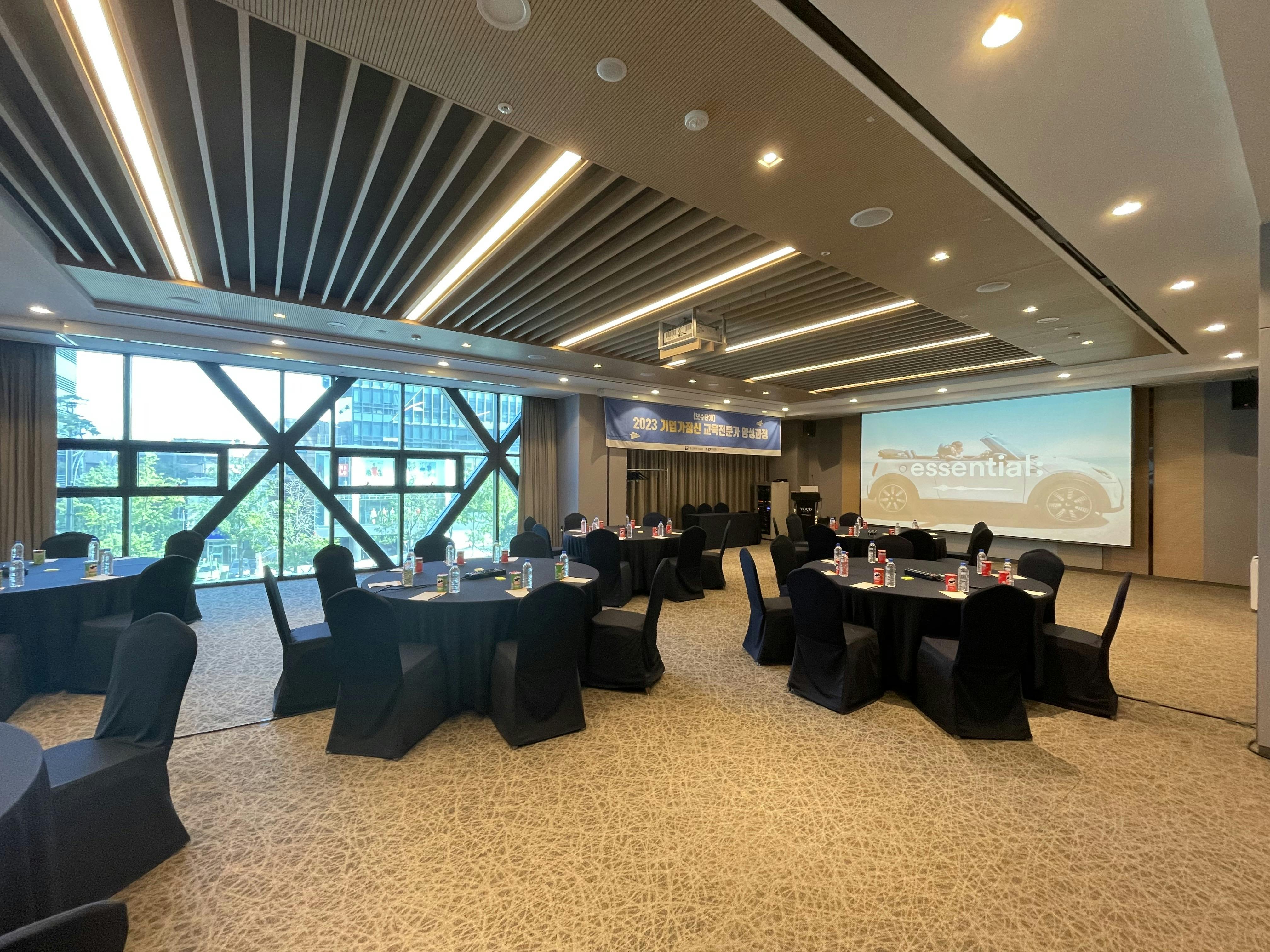 Modern meeting room in voco Seoul Gangnam, featuring round tables for events and presentations.