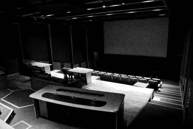 Versatile event space with tiered seating for presentations and screenings in ALL IS JOY.