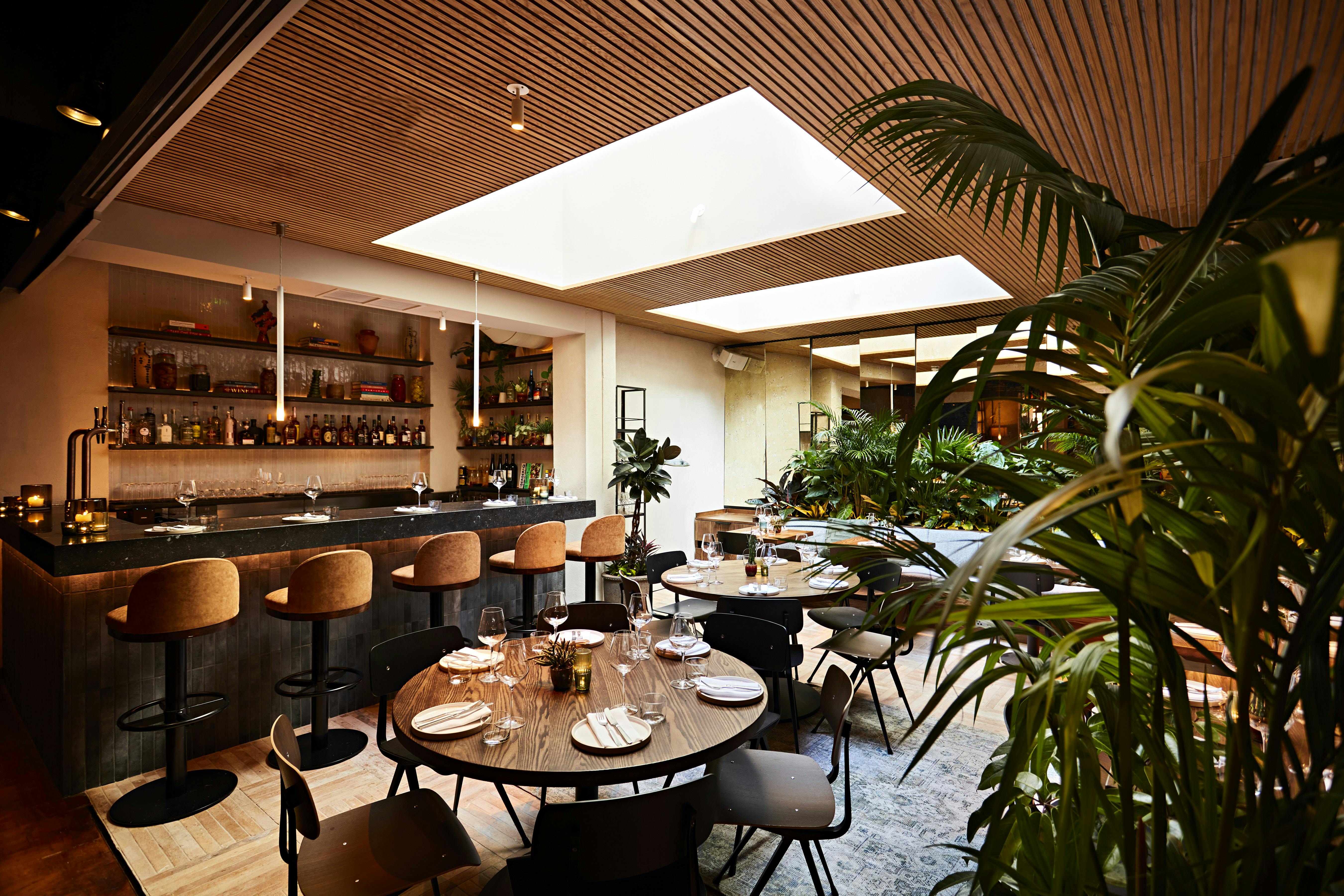 Stylish restaurant interior with greenery, perfect for corporate events and gatherings.