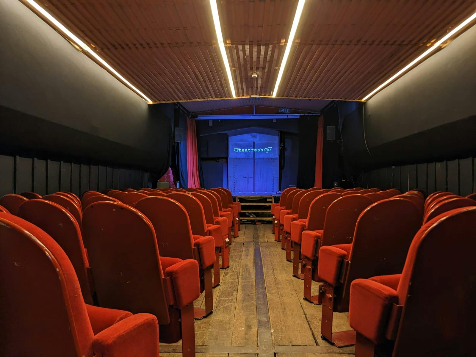 Event space with red seating and stage, ideal for presentations and workshops.