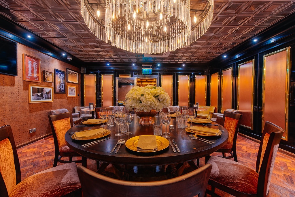 Elegant meeting room with round table and chandelier for upscale events and private dinners. - Banner