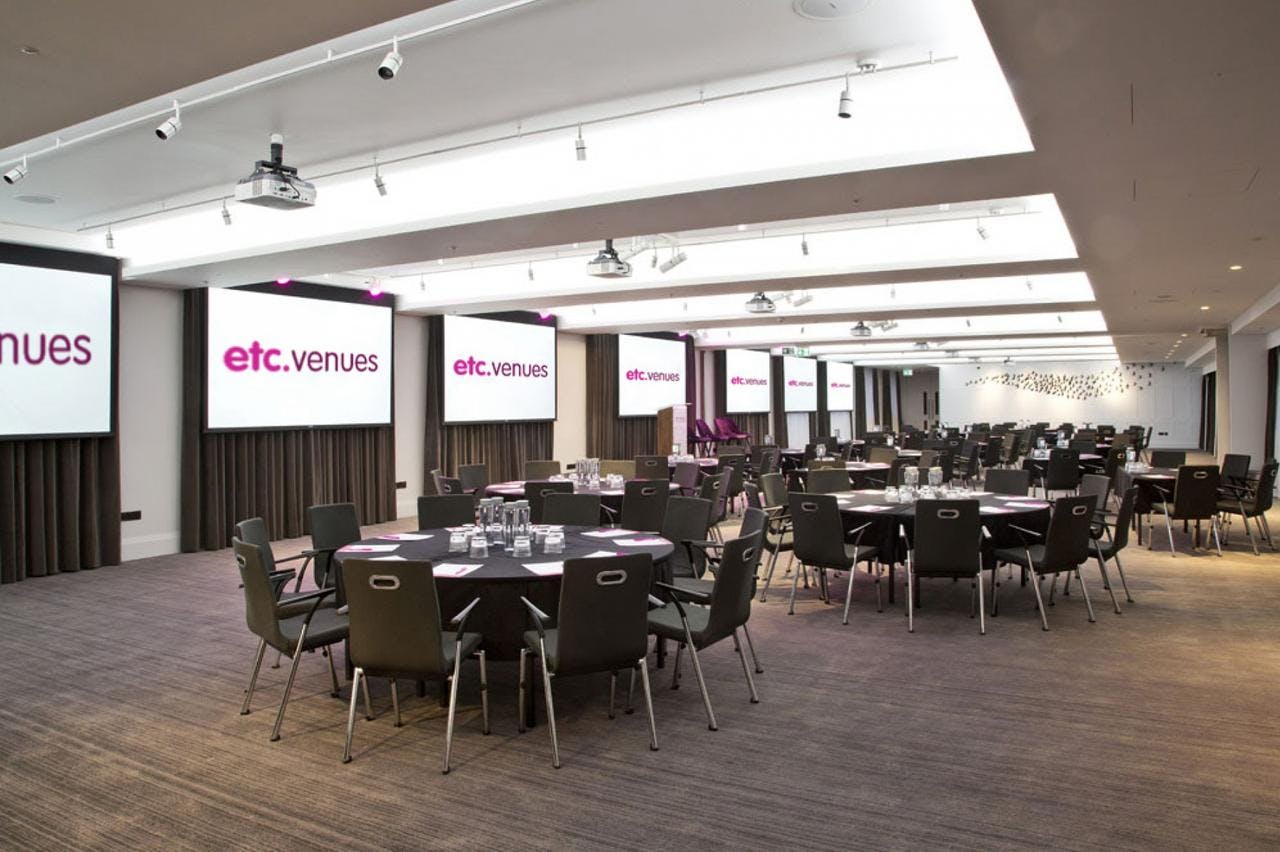 Modern event space at etc.venues County Hall with round tables for corporate meetings.