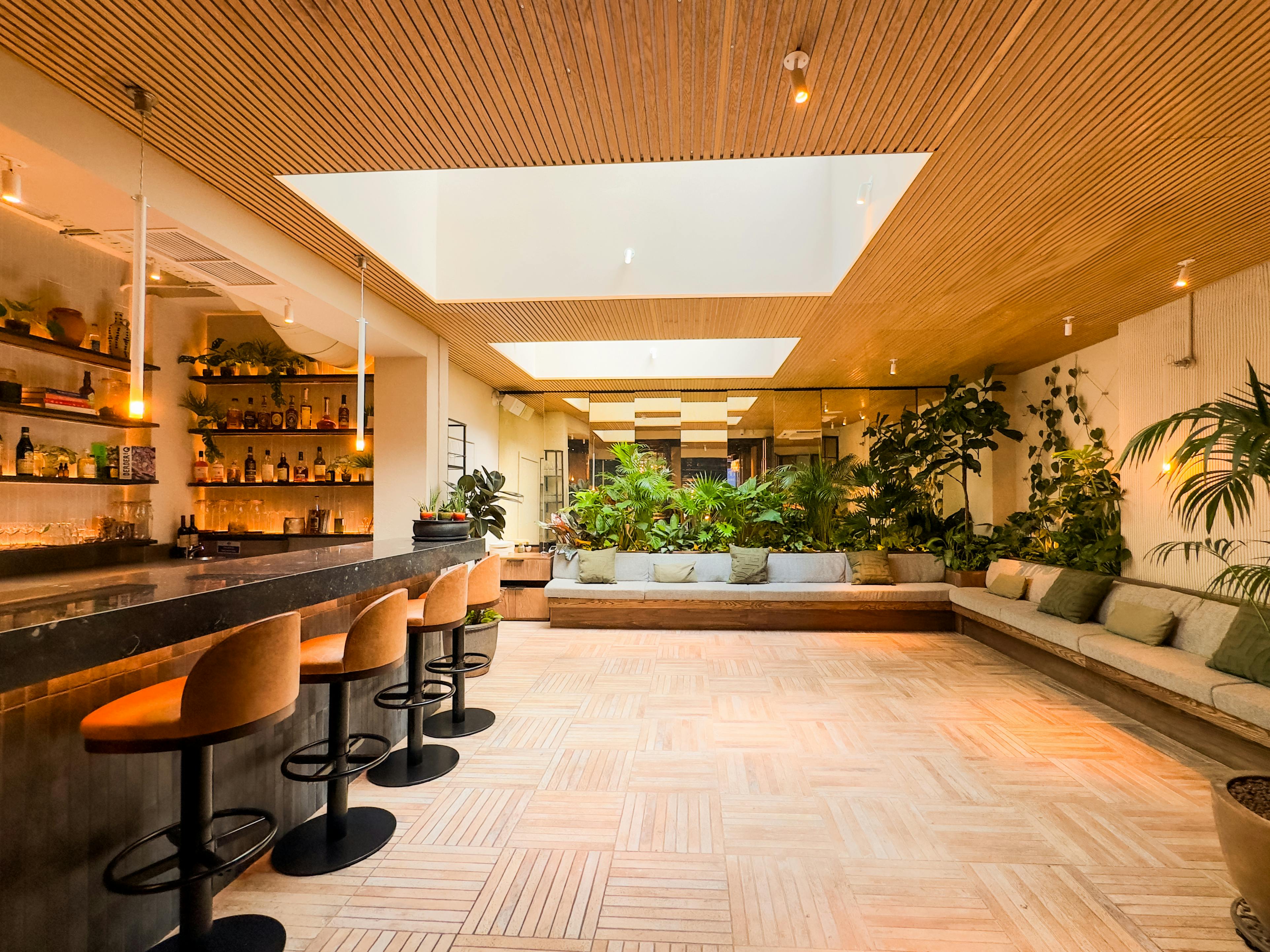 Stylish event space with bar and greenery, ideal for networking in Carmel Fitzrovia.