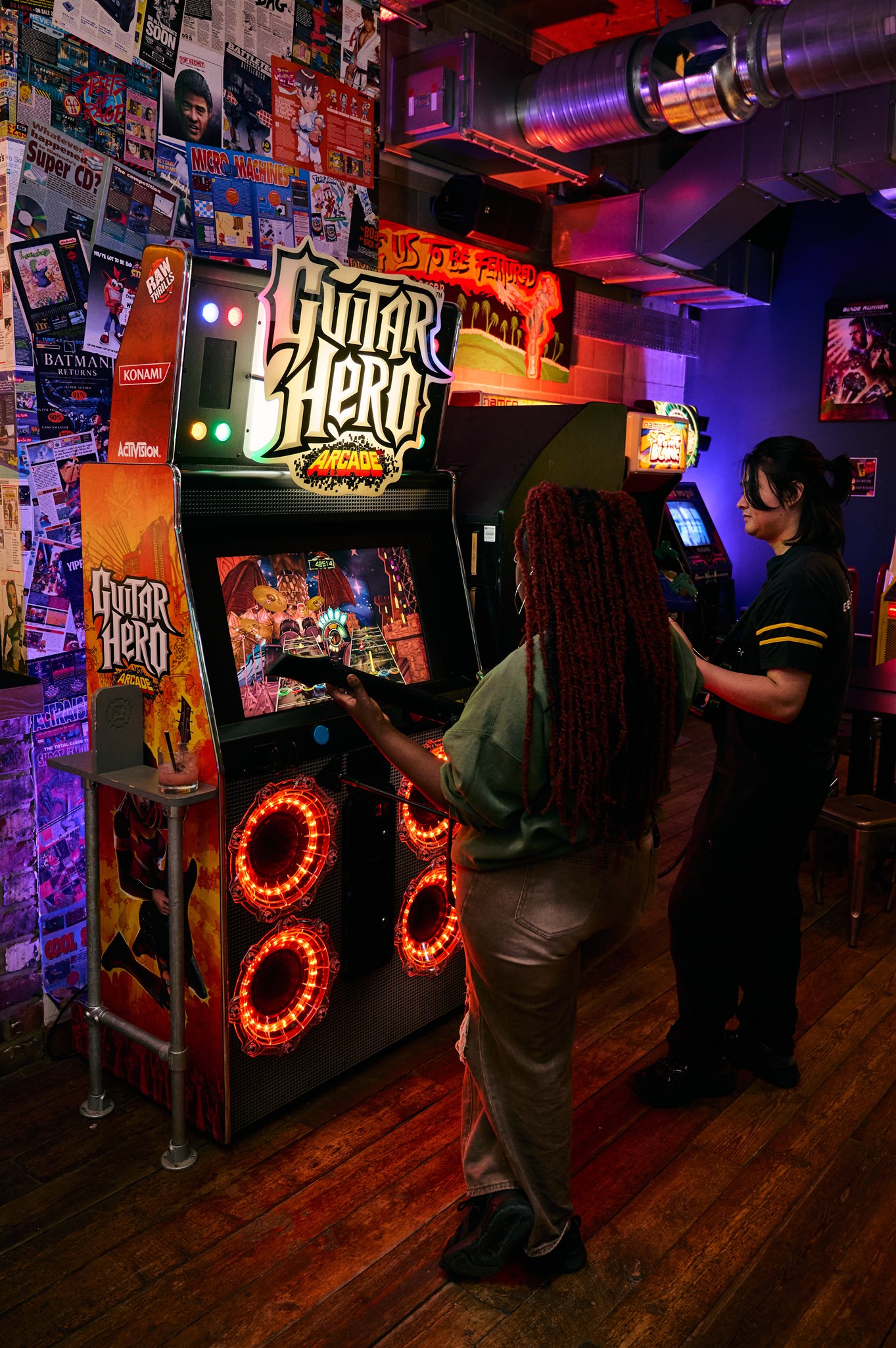 "Vibrant arcade venue hire with guests playing Guitar Hero for events and entertainment."