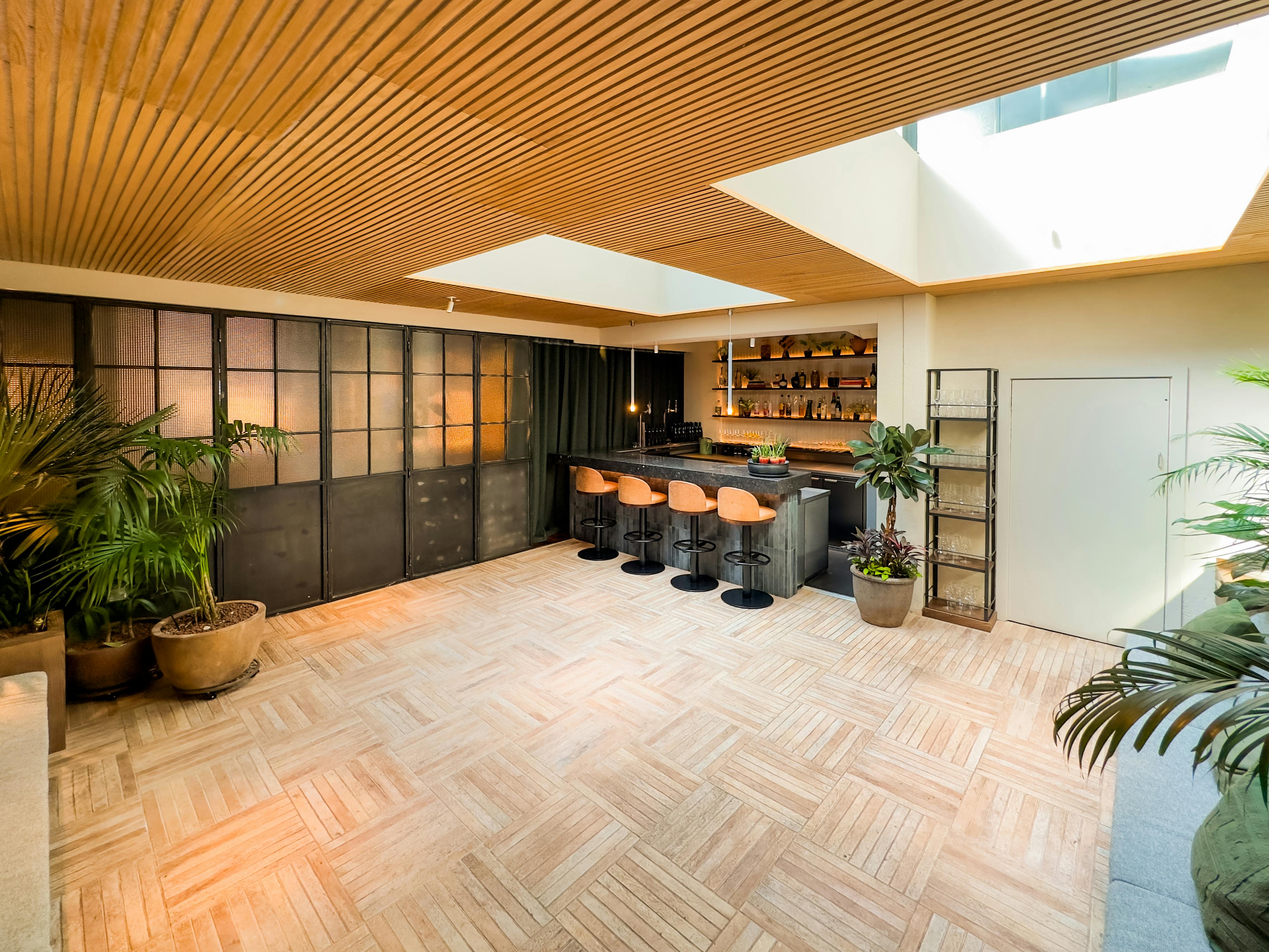Stylish event venue in Carmel Fitzrovia with modern bar and lush greenery, perfect for gatherings.