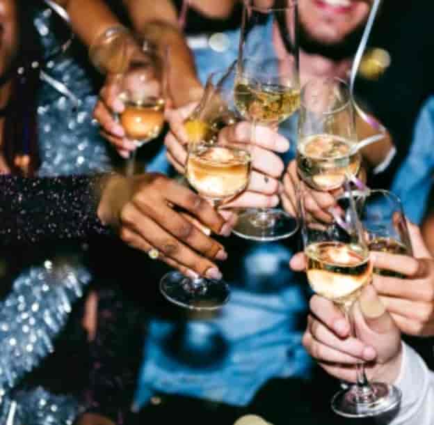 Vibrant celebration at IKON Event Space with attendees toasting champagne glasses.