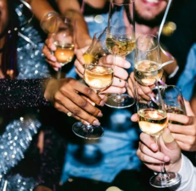 Vibrant celebration at IKON Event Space with attendees toasting champagne glasses.