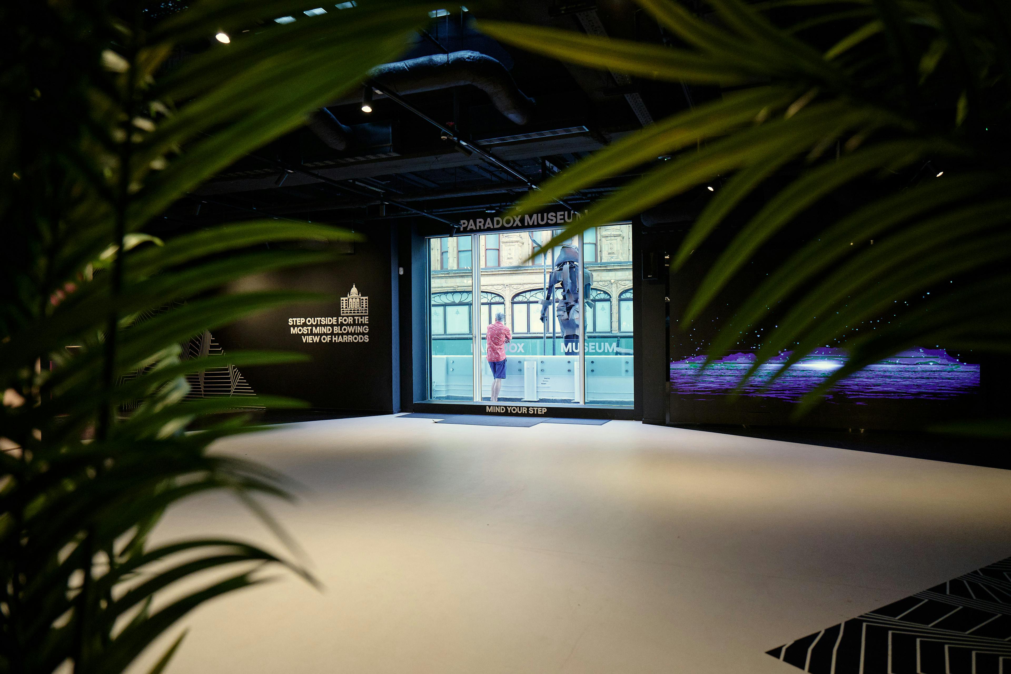 Modern event space in Paradox Museum London with large screen and lush greenery.