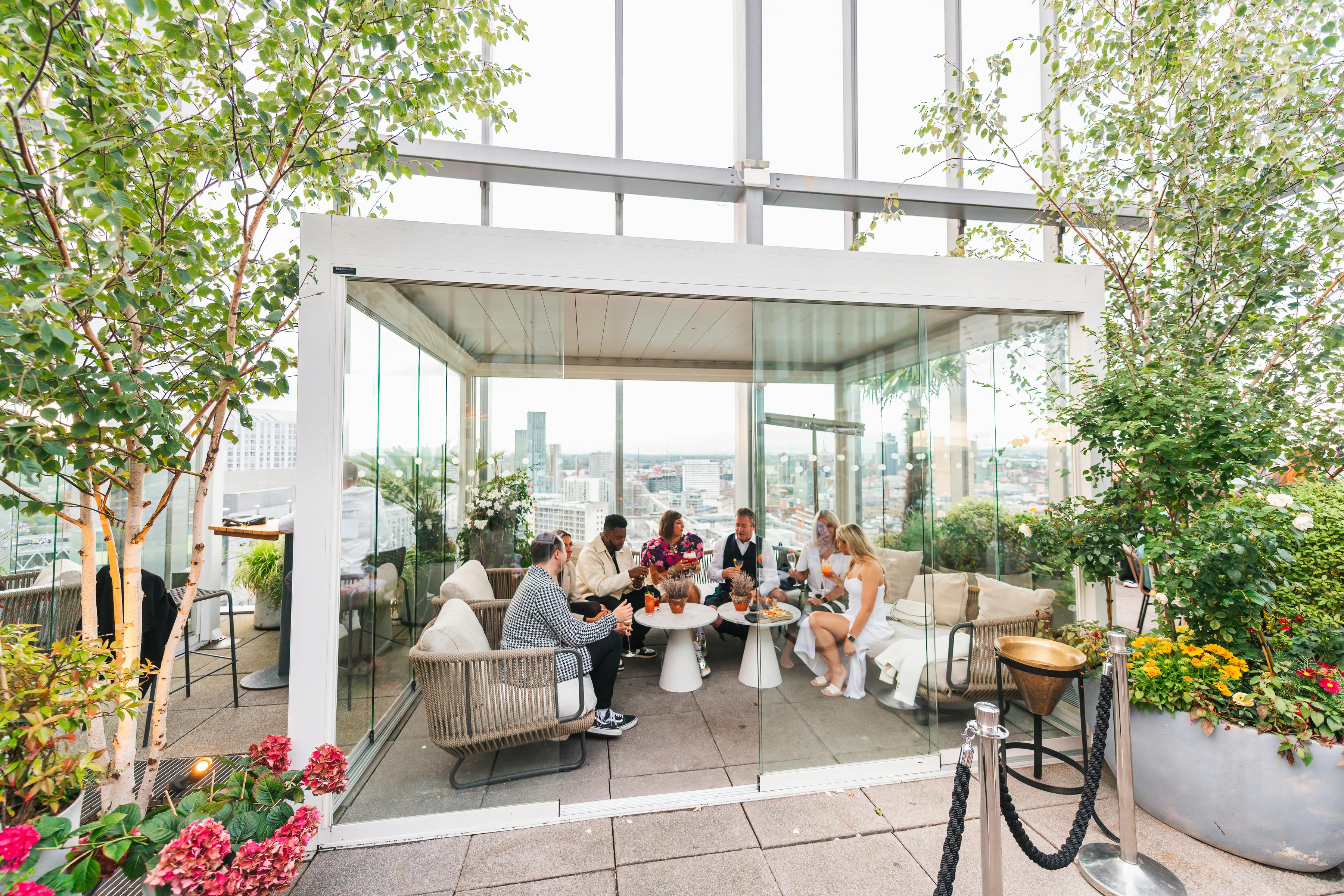 Rooftop glass-enclosed pergola for corporate events with city skyline backdrop.