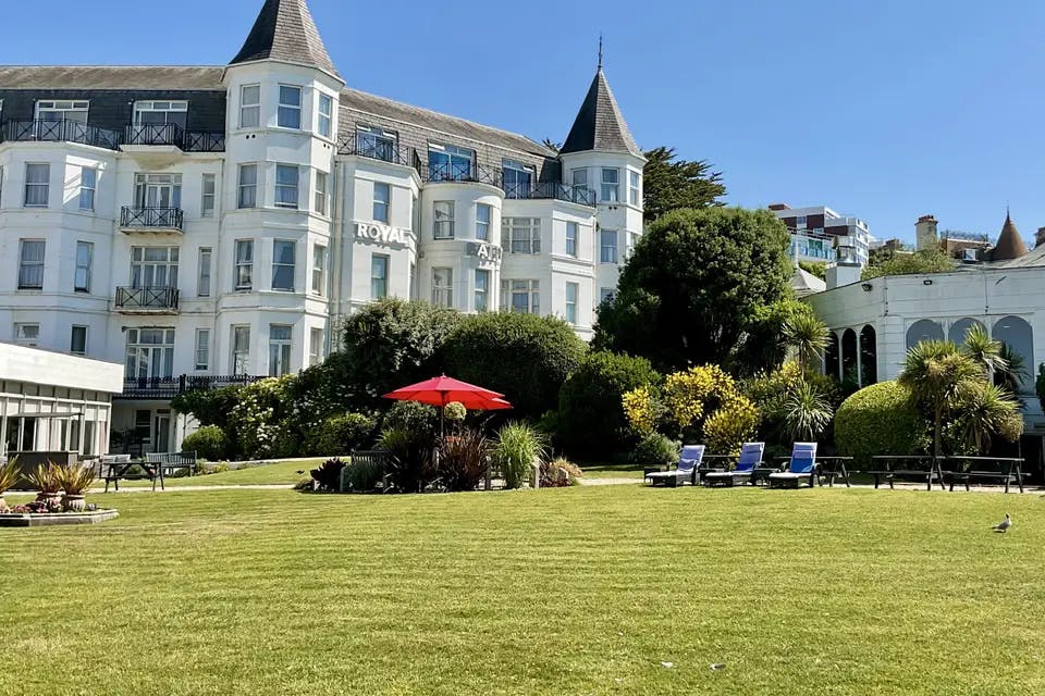 Secret Garden at Royal Bath Hotel: lush lawn, red umbrella, ideal for outdoor events.