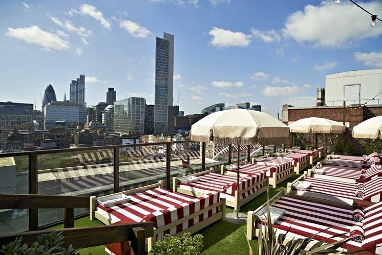 Stylish Shoreditch House rooftop venue with lounge beds, ideal for summer events.