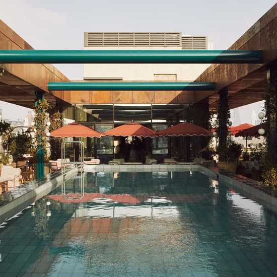 Rooftop pool at Shoreditch House with elegant seating and vibrant red umbrellas for events.