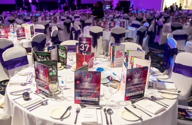 Elegant banquet setting with white linens and purple sashes for formal events.