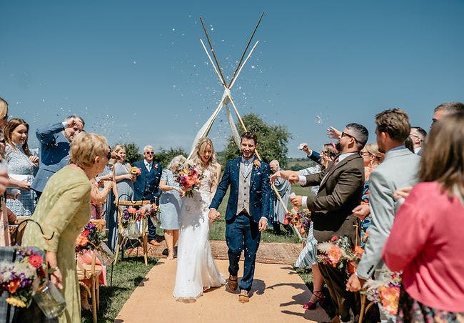 Outdoor wedding ceremony under decorated tipi with confetti at Belcote Farm.