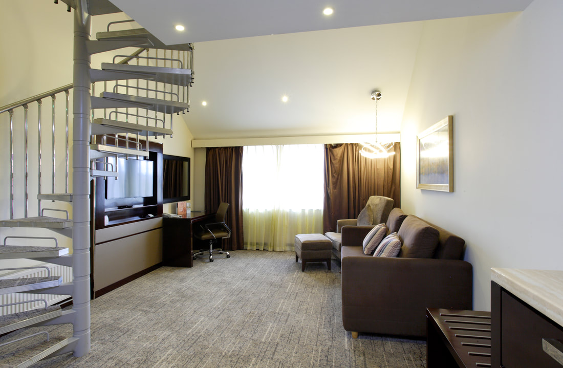 Modern meeting room with cozy seating and spiral staircase at Ramada Solihull Birmingham. - Banner
