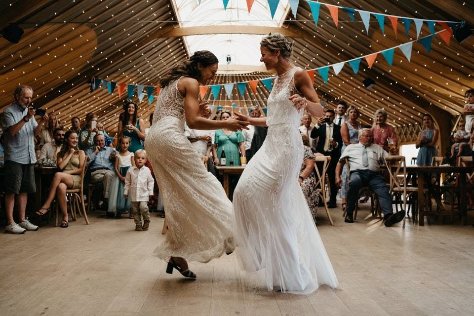 "Vibrant wedding reception in Thorpe Garden's Ceremony Room with dancing brides and rustic decor."