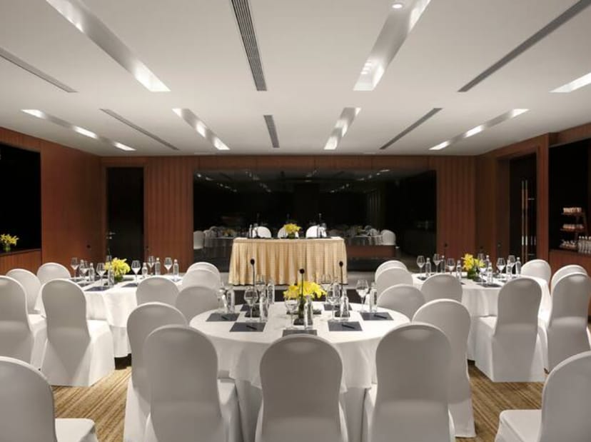 Meeting room with round tables and yellow flower centerpieces in Hilton Embassy Golf Link.
