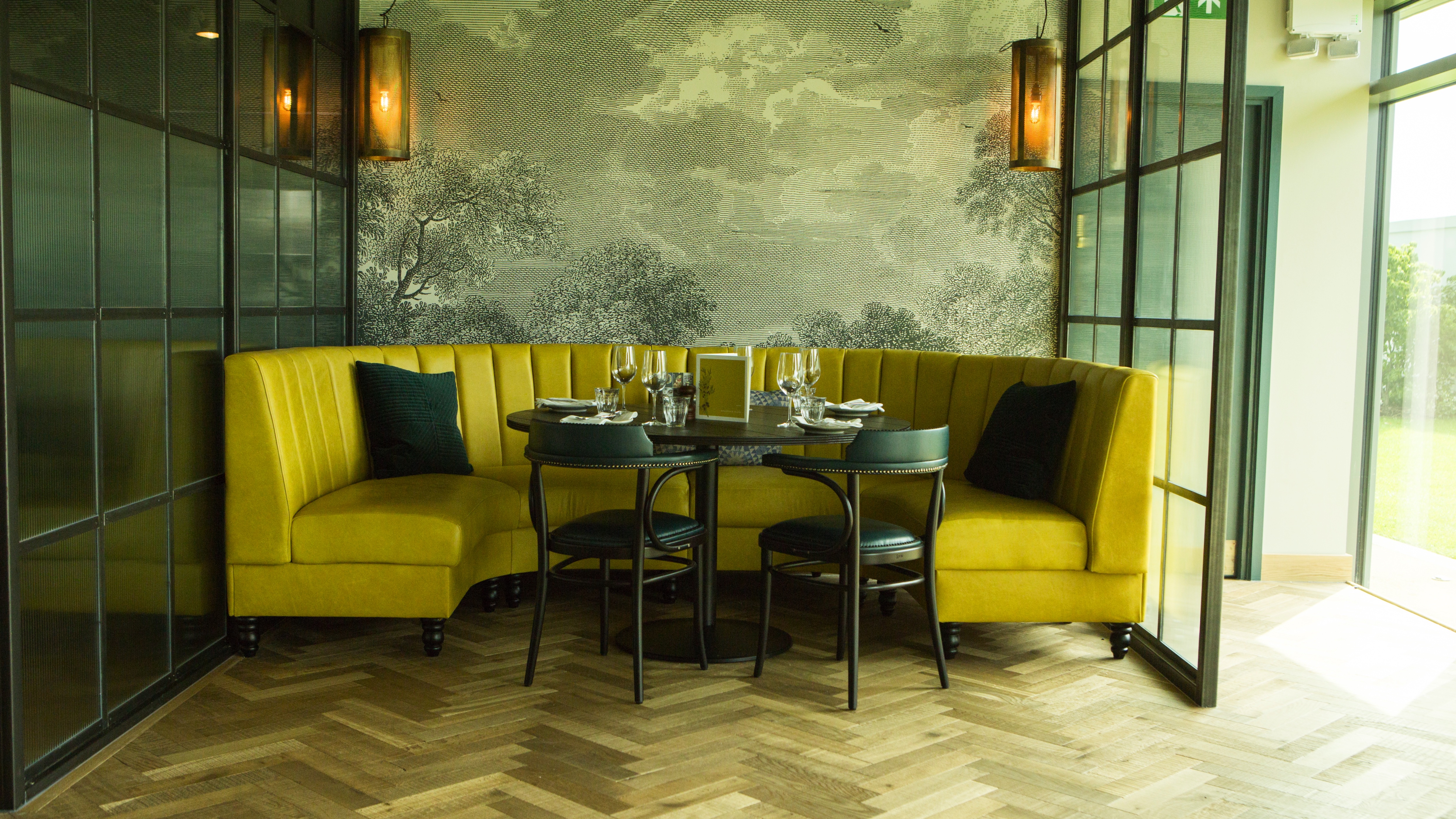 Semi-private meeting space with yellow banquette, ideal for networking events.