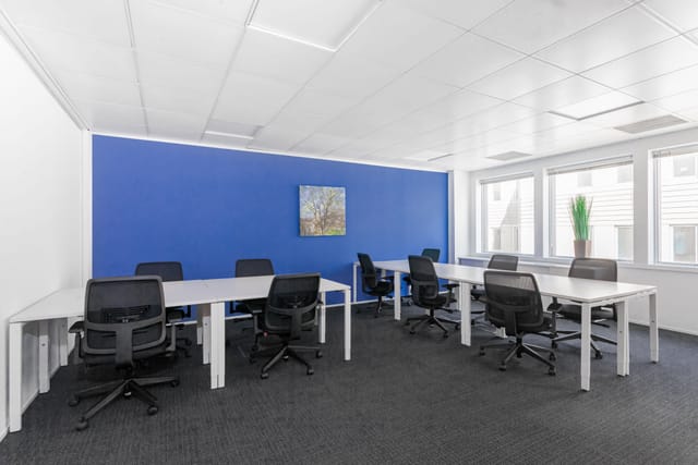 Modern meeting room with blue accent wall, ideal for workshops and team discussions.