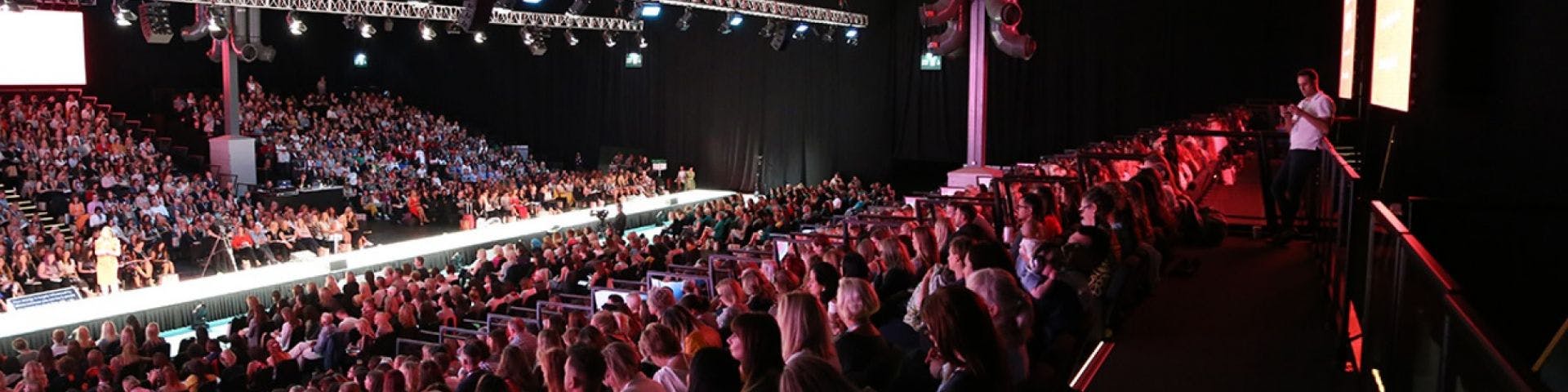 Packed auditorium at NEC Birmingham for a dynamic event with tiered seating.