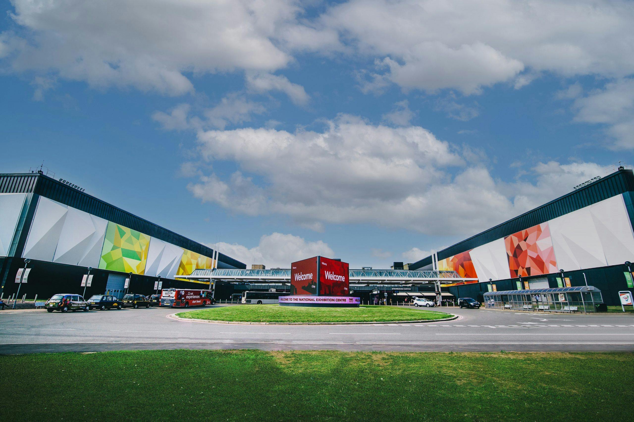 Modern NEC Birmingham auditorium with vibrant murals, perfect for conferences and exhibitions.