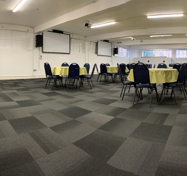Versatile event space with yellow tablecloths for meetings and gatherings at OIKOS Café.