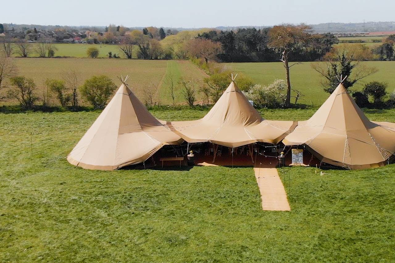 Spacious outdoor event venue with elegant tipis, perfect for weddings and festivals.