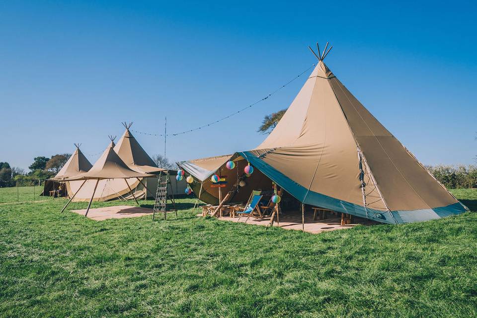 Outdoor event space with stylish tipis, ideal for weddings and festivals. - Banner