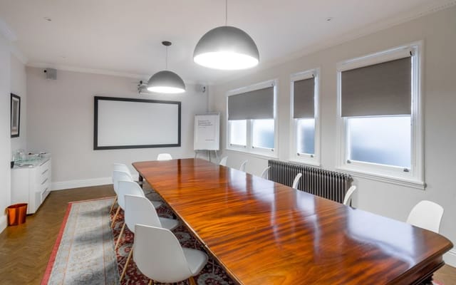 Modern meeting room with wooden table, ideal for collaborative brainstorming sessions.