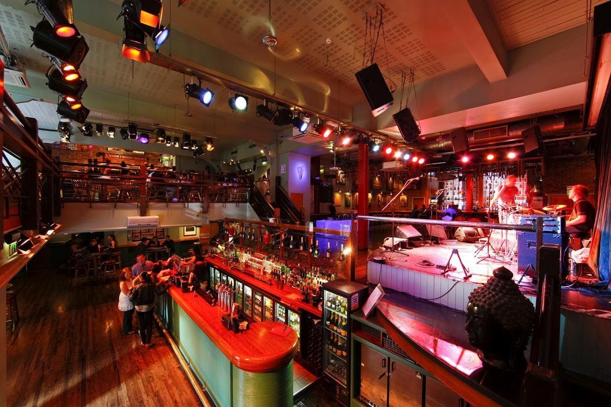 Vibrant balcony event space with bar, ideal for networking and live music gatherings.