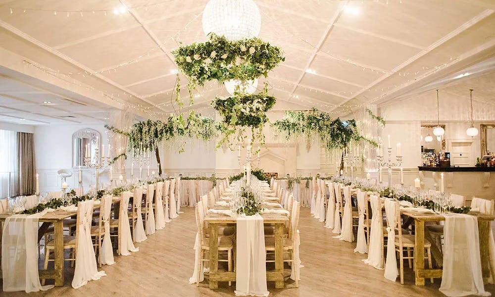 Elegant Christmas party setup with lush greenery and chandelier at Manor by the Lake.